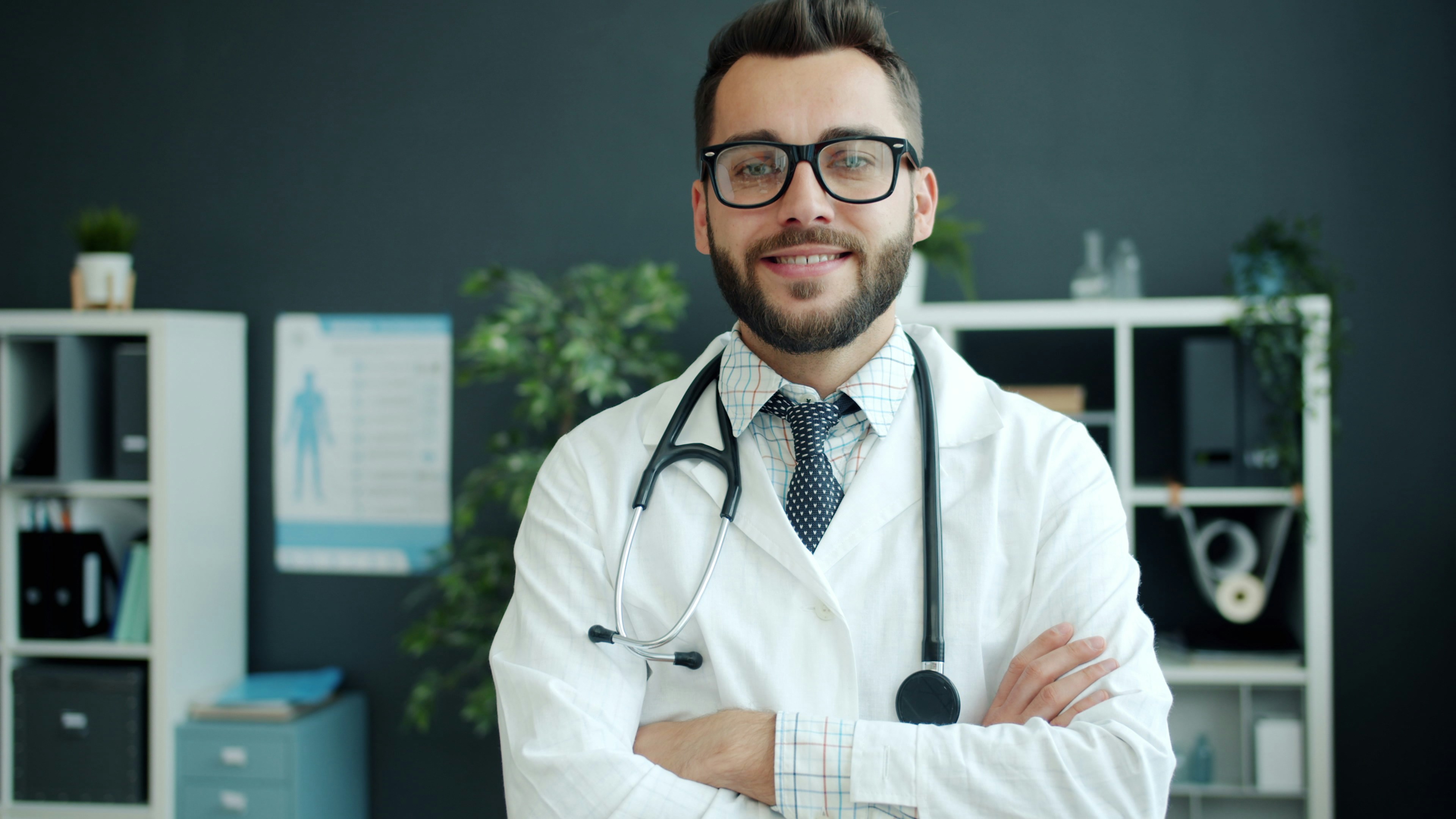 Confident physician standing arms crossed in a modern clinic